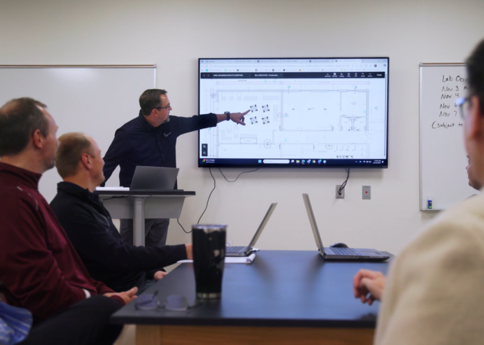 Performance Services team member pointing to school renovation plans on a screen