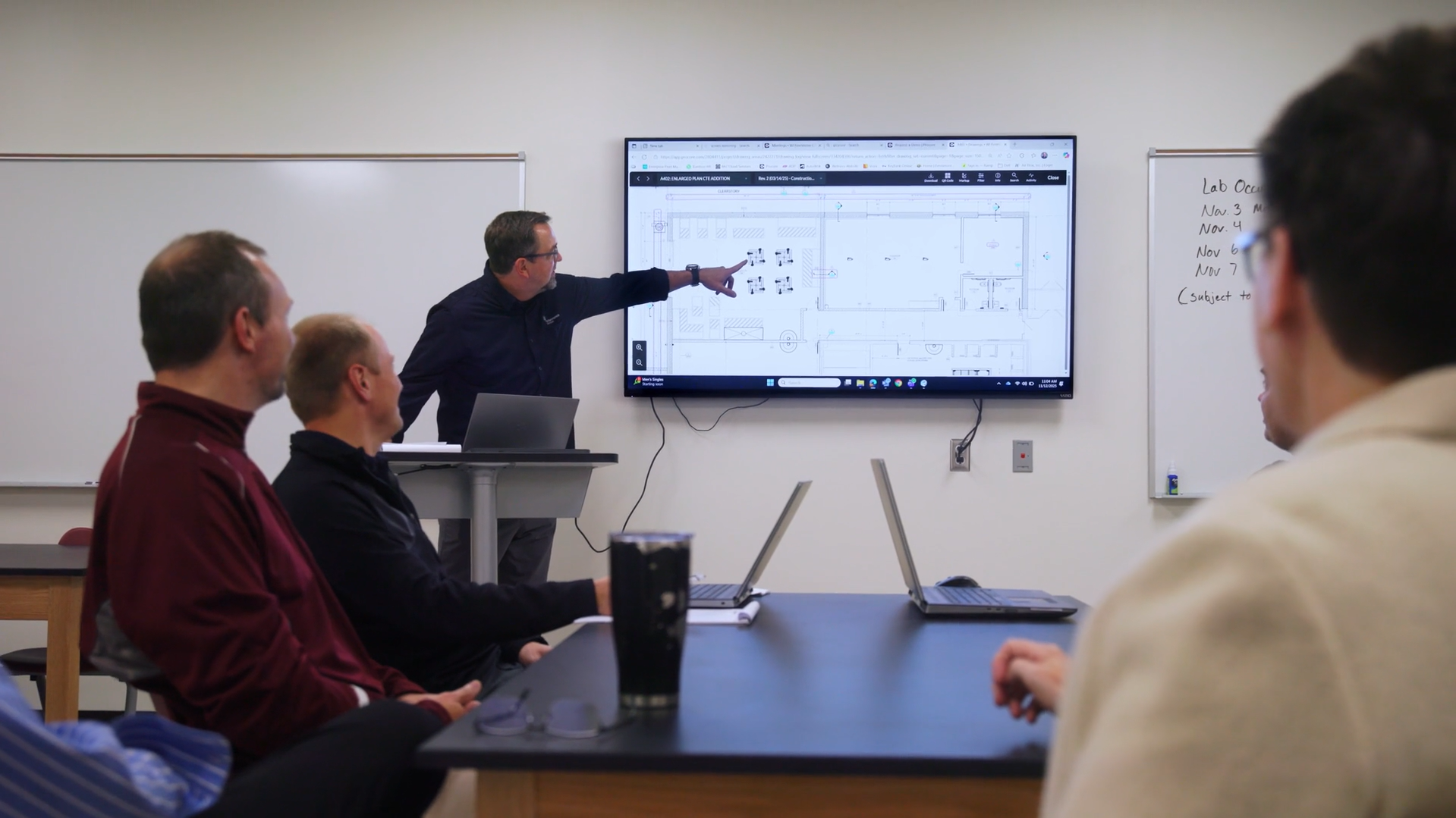 Performance Services team member pointing to school renovation plans on a screen