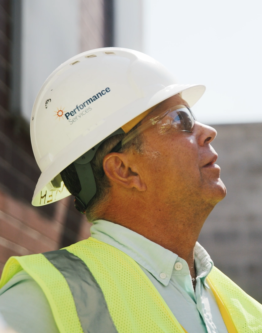 Performance Services' Project Manager on a job site in a hard hat, safety glasses, and vest