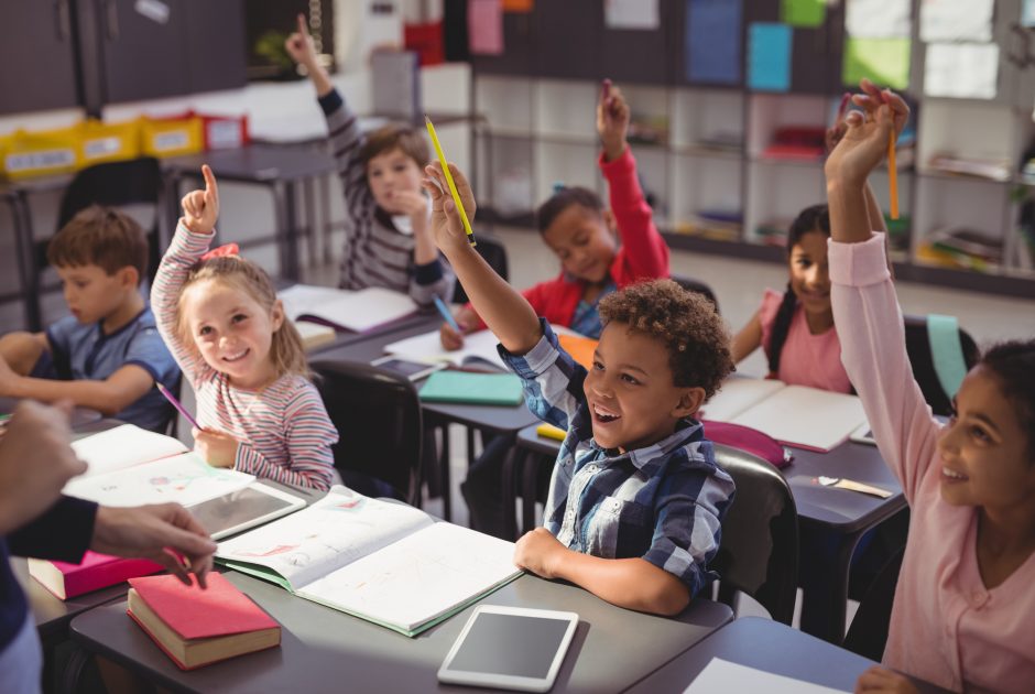 K-12 students participating in class with their hands raised