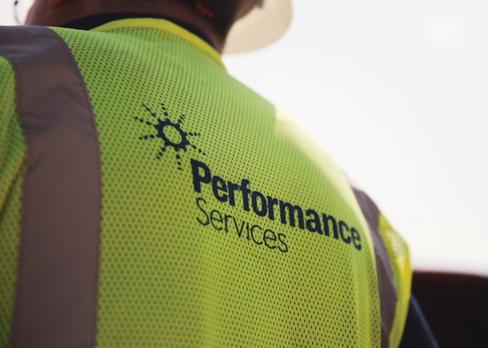 Closeup of the Performance Services logo on the back of a project manager's safety vest