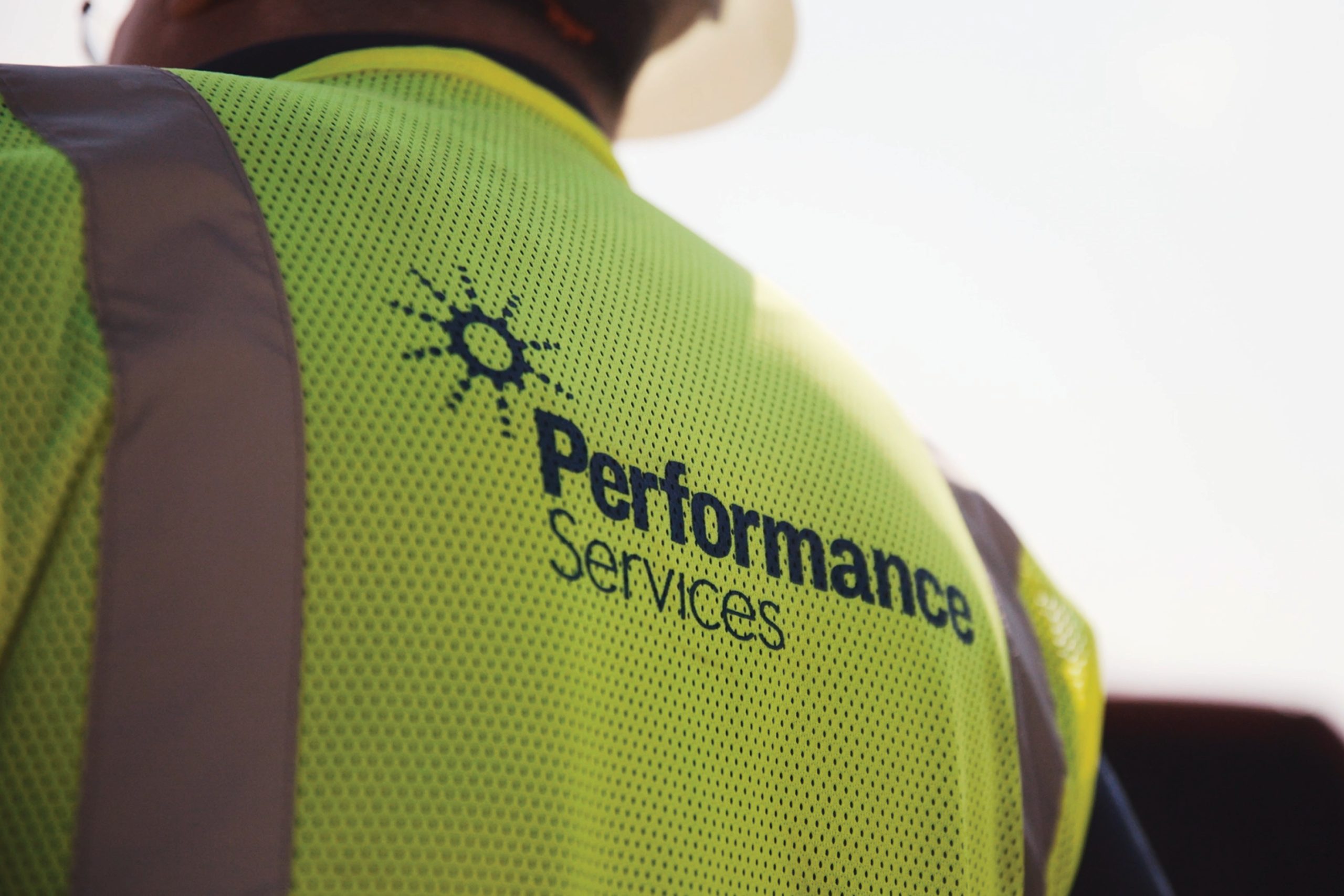 Closeup of the Performance Services logo on the back of a project manager's safety vest