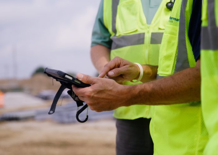 Performance Services employees in PPE reviewing construction documents on a tablet