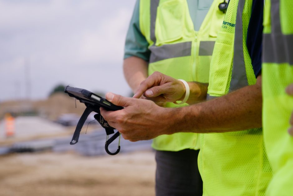 Performance Services employees in PPE reviewing construction documents on a tablet