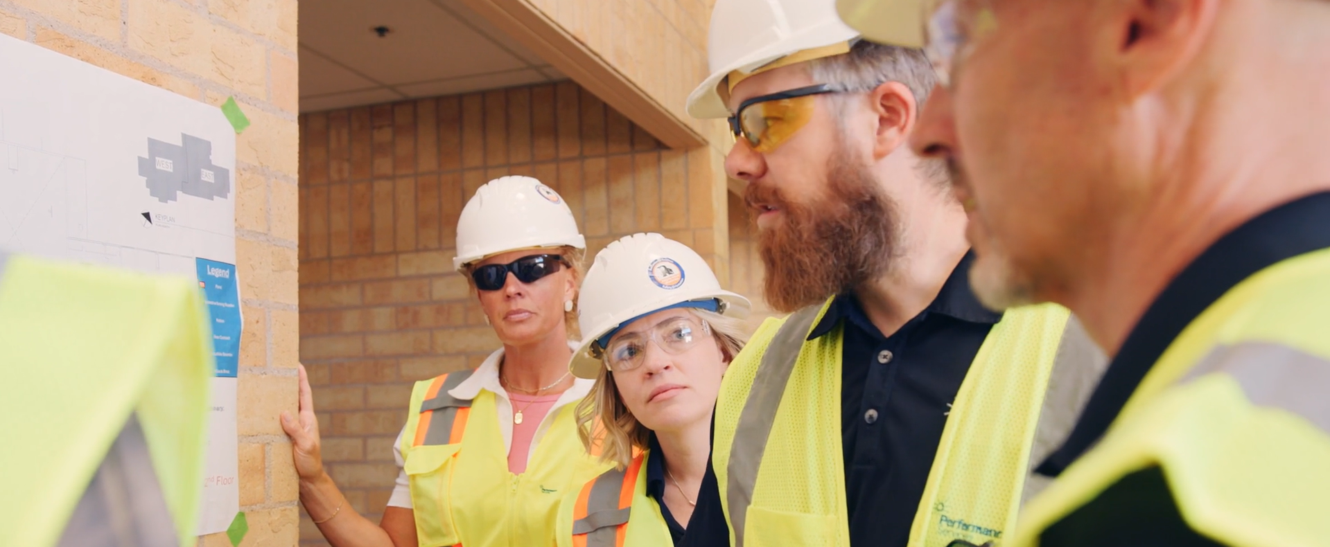 Colorado team members in proper PPE huddled around project plans at a K-12 school