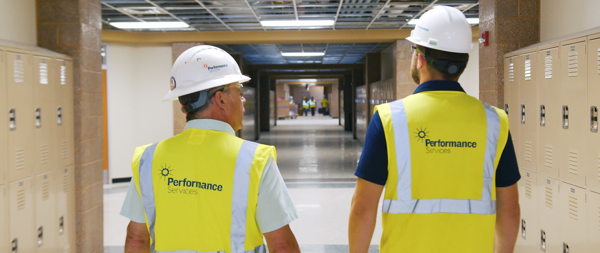 Two project managers walking an active construction in safety vests and hard hats