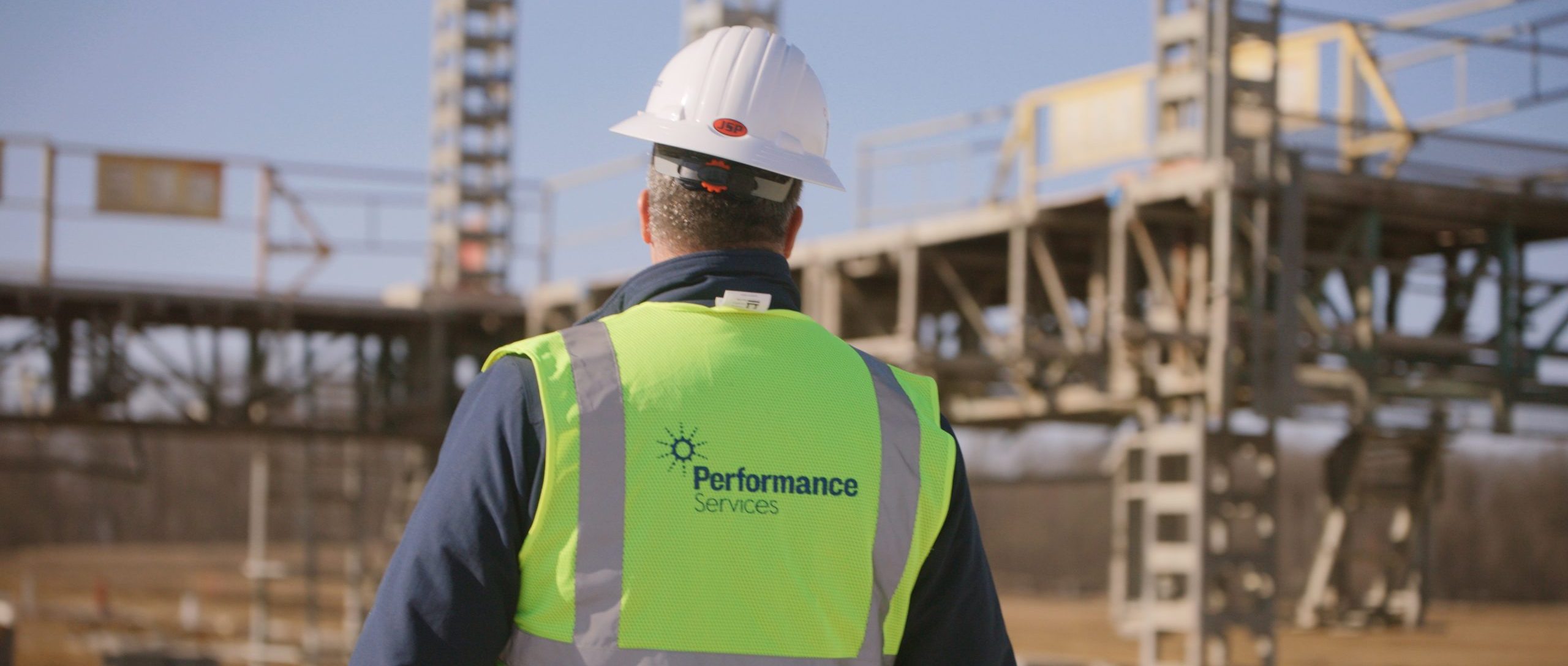 Performance Services team member walking at a jobsite in a safety vest and hard hat