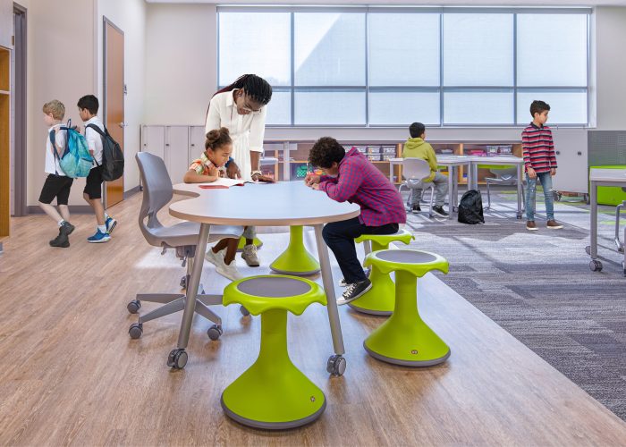 Students working on a project at a table in a classroom with a teacher helping