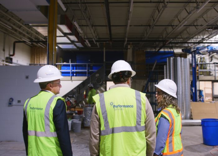 Performance Services team members collaborating at a project design-build site wearing proper PPE
