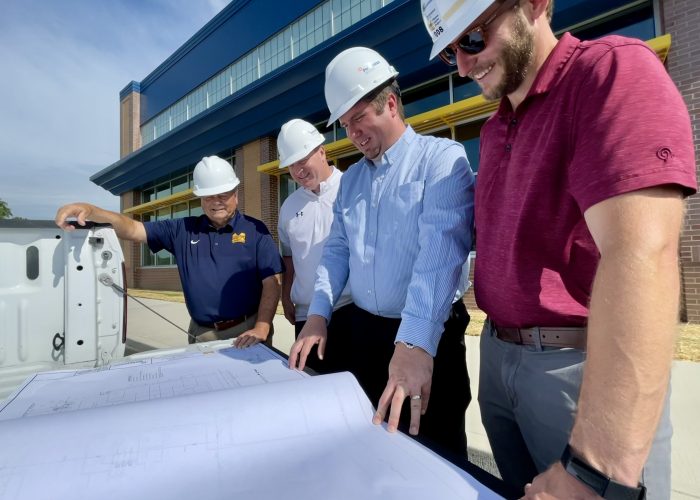 Performance Services team members in hardhats looking at project plans with a client