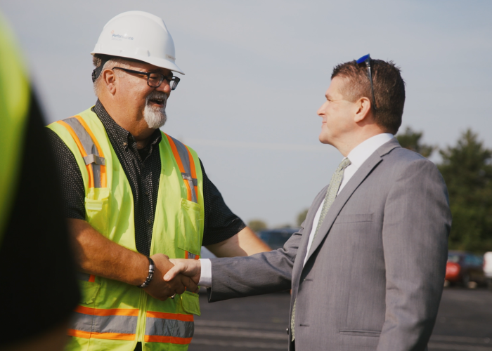 Performance Services project manager in a hardhat shaking hands with a customer