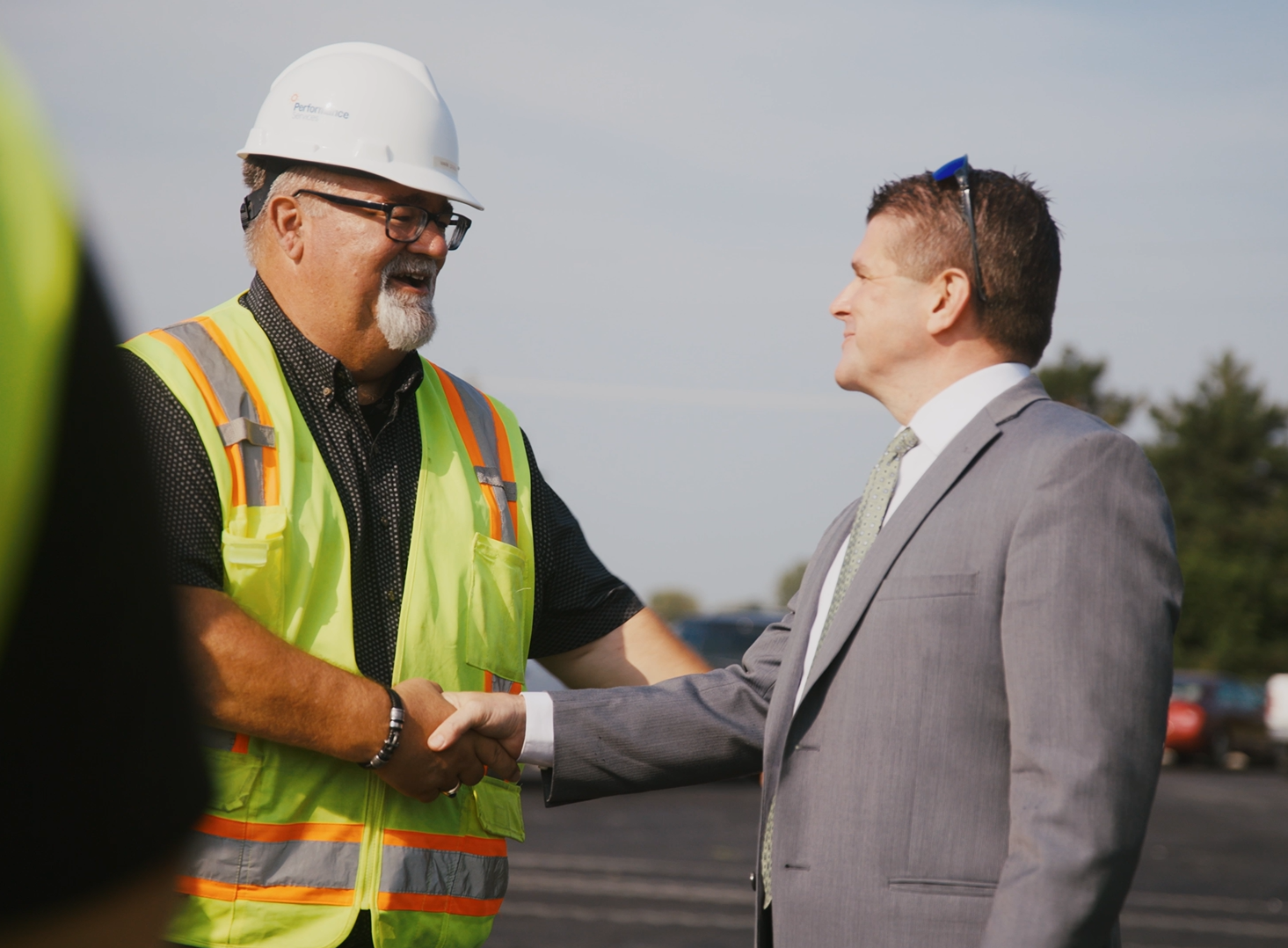 Performance Services project manager in a hardhat shaking hands with a customer