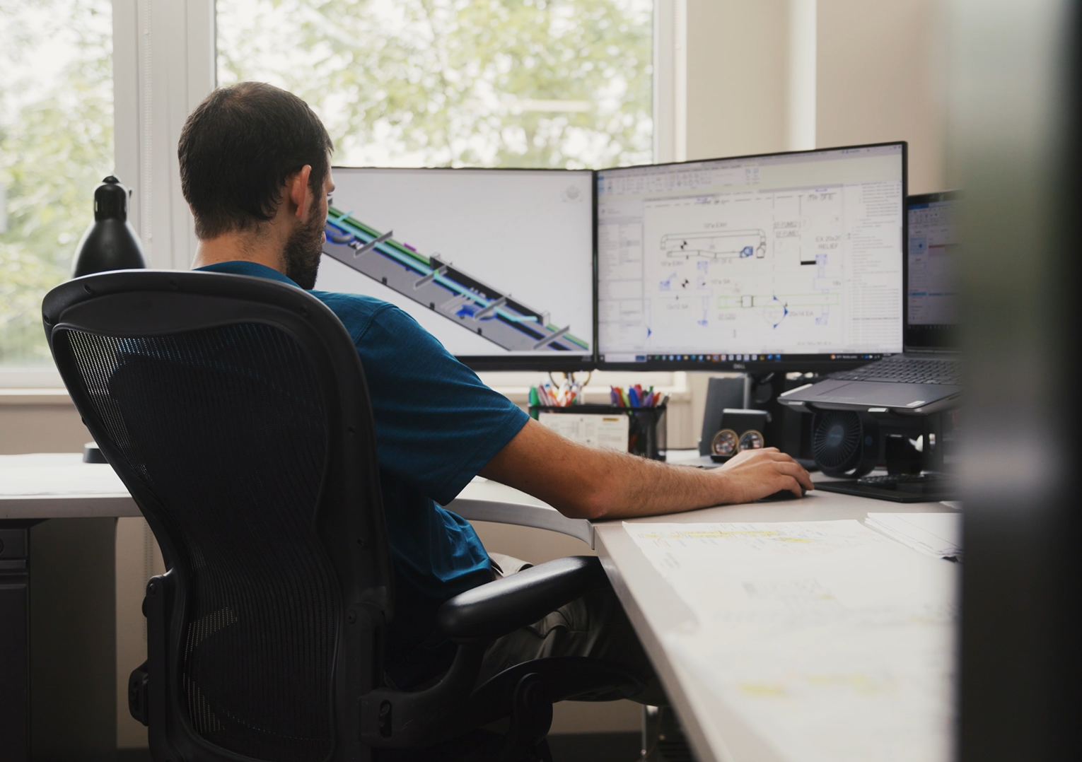 Performance Services engineer working on MEP design plans on a computer