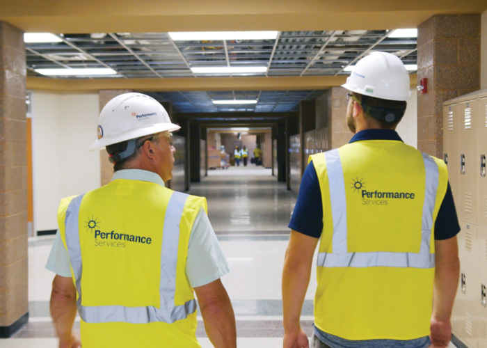 Performance Services team in safety vests and hardhats walking through a school building