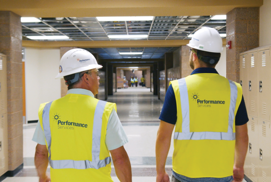 Performance Services team in safety vests and hardhats walking through a school building