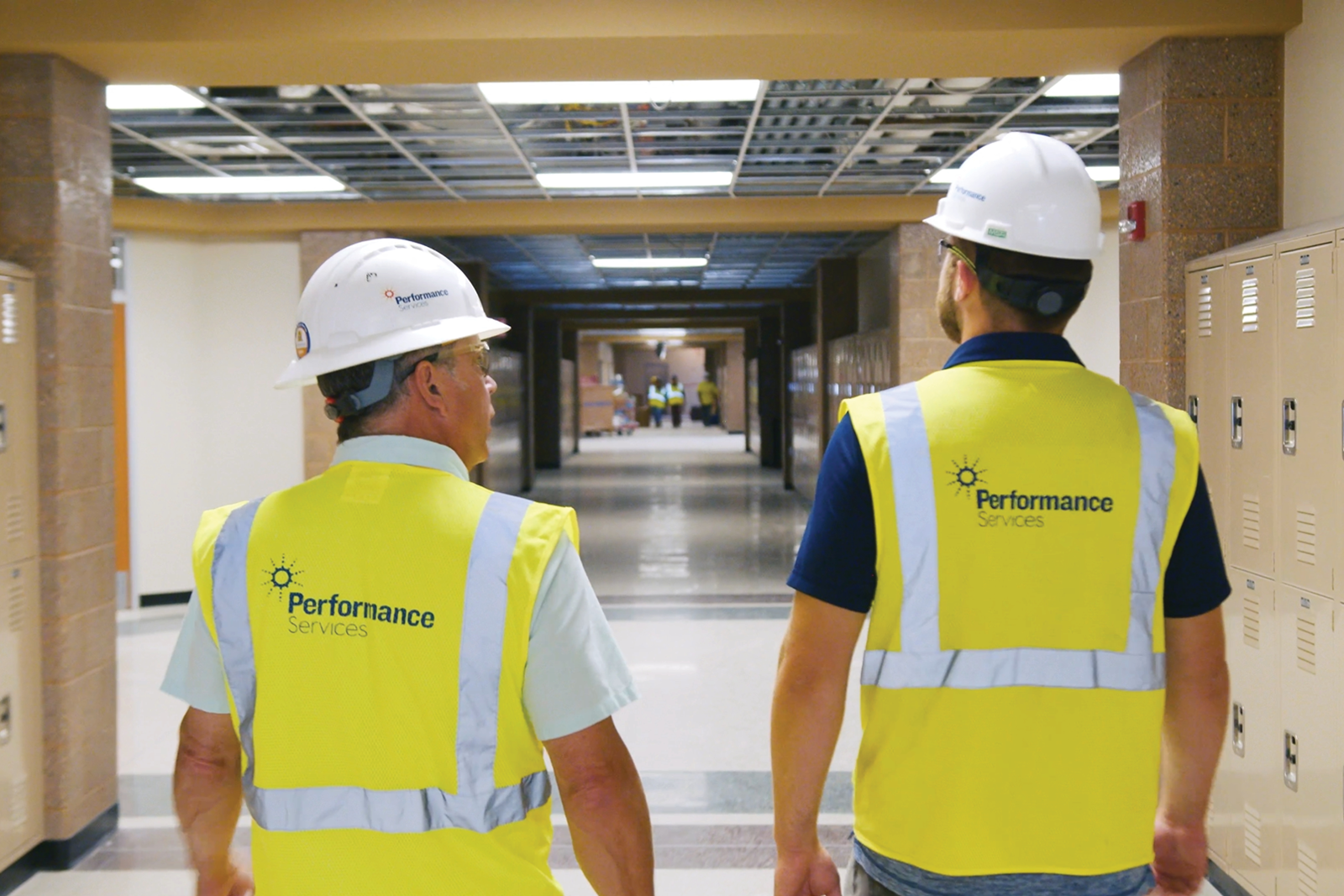 Performance Services team in safety vests and hardhats walking through a school building